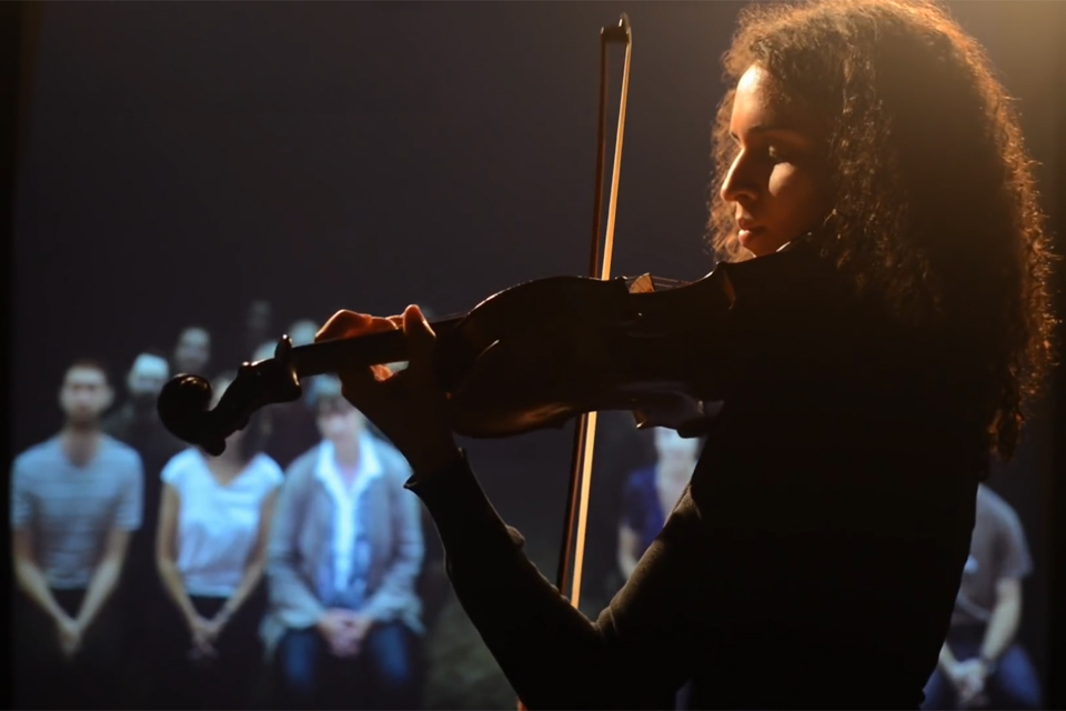 A silhouette of a black student, playing a violin, with people watching them perform.